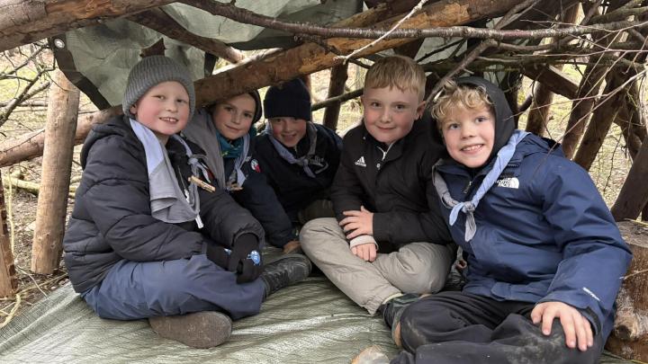 Spejderbørn i en hule de selv har bygget af pinde