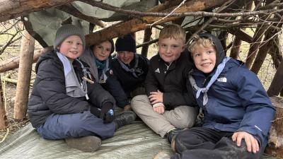 Spejderbørn i en hule de selv har bygget af pinde